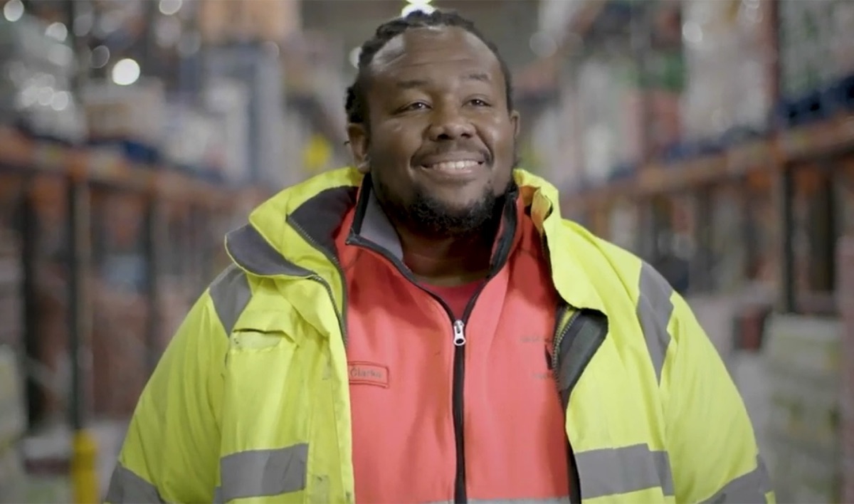 Still from the Coca-Cola Safety Series: a warehouse worker in hi-vis smiling at camera.