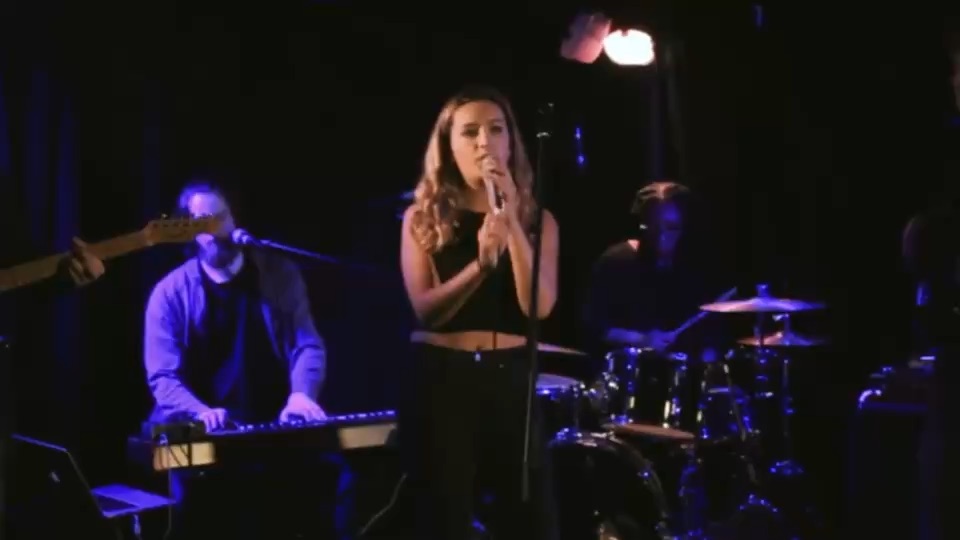 Frame from Gracie at the Troubadour: a singer on stage in blue light.