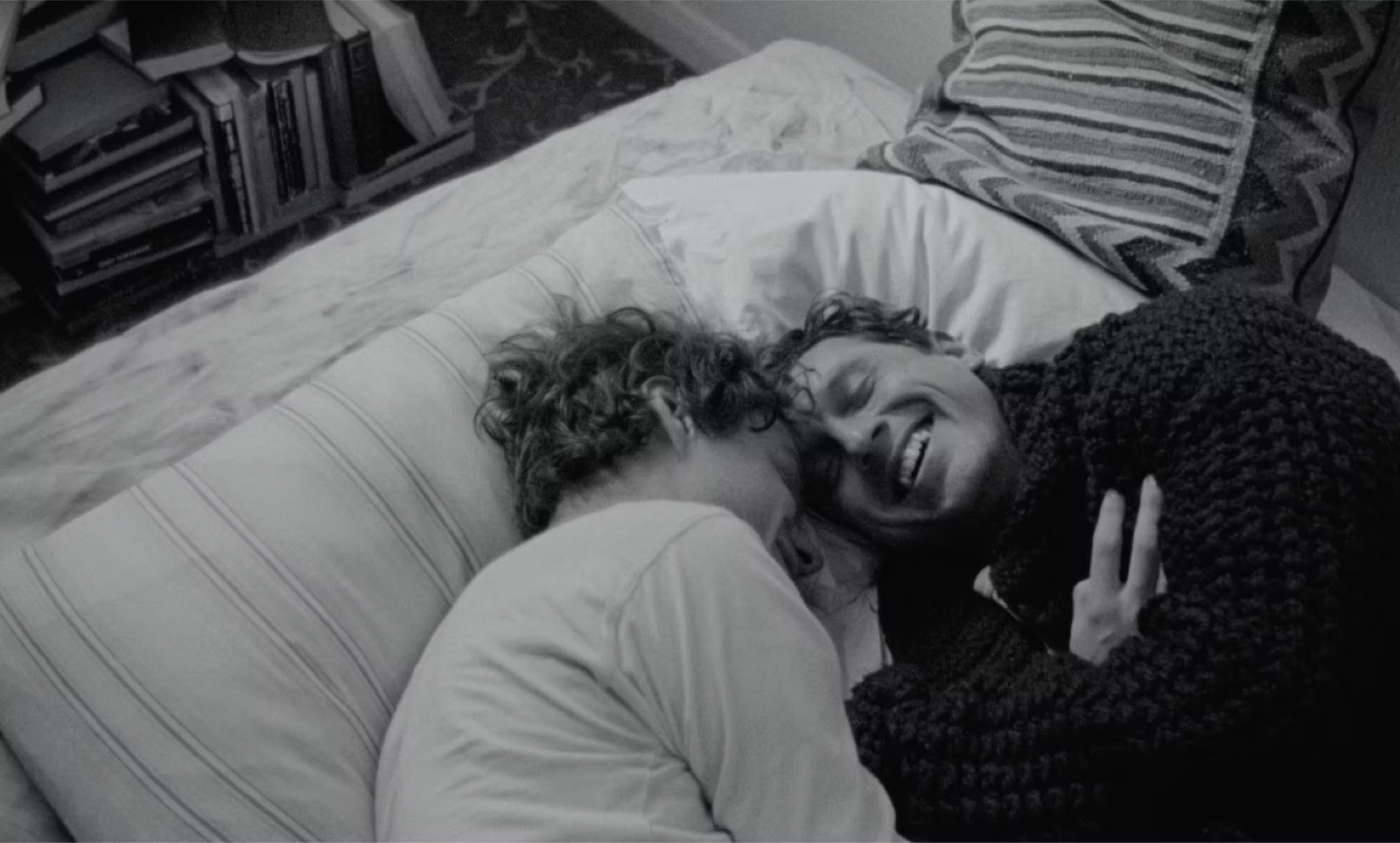 Still from The Generators: a couple laughing together on a bed, in black and white.