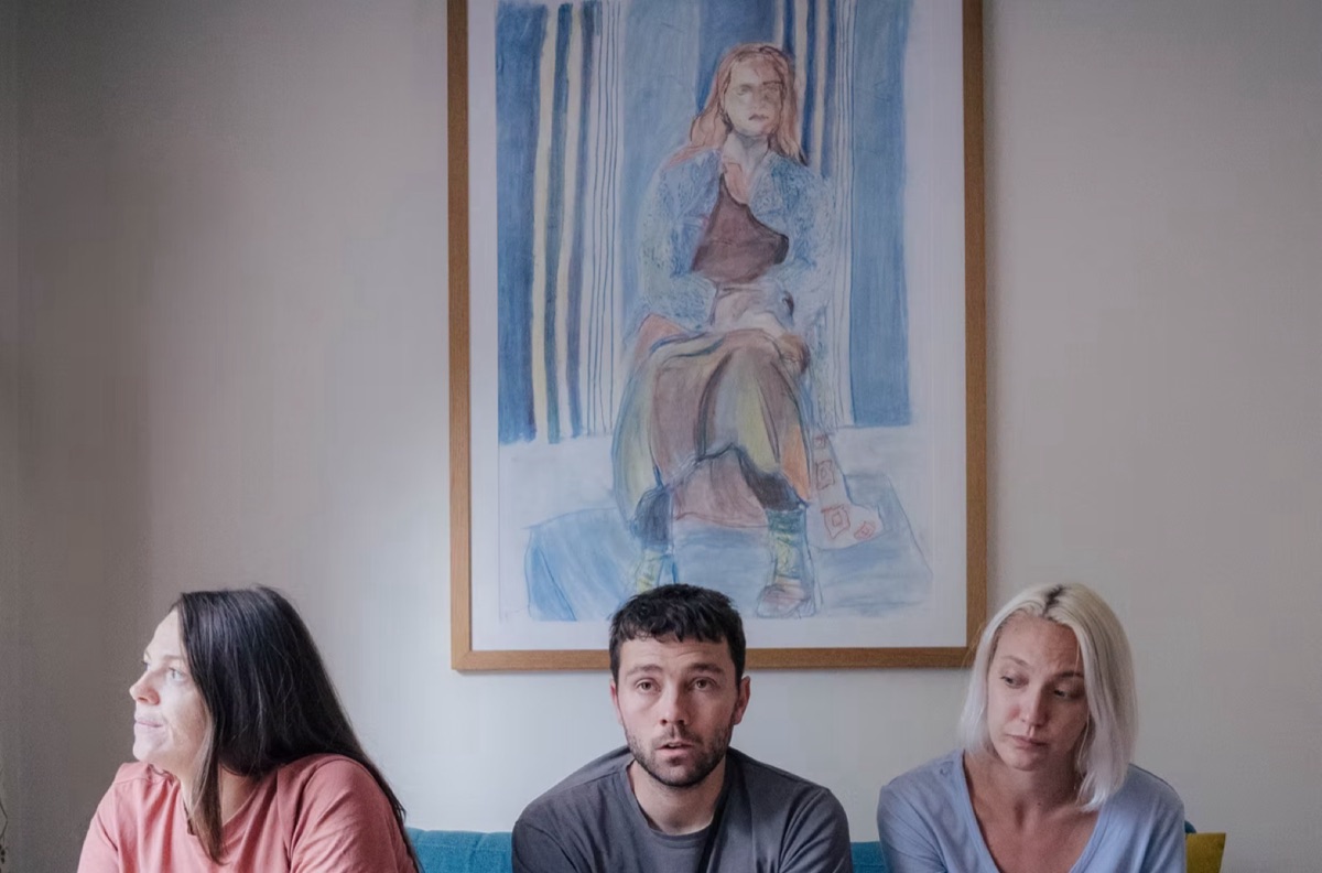 Still from These Walls: three people sitting on a sofa beneath a framed portrait.