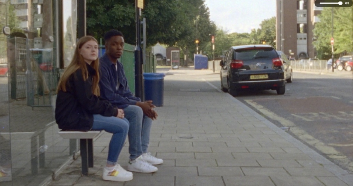 Still from Young Minds 'Act Early': two teenagers sitting at a bus stop.