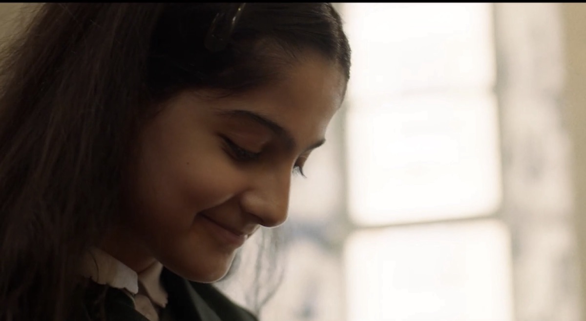 Still from Zara's Story: a young girl smiling as she looks down.